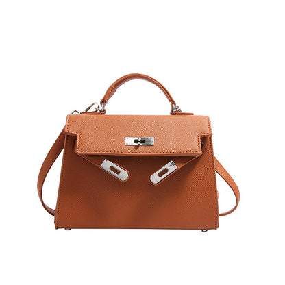 A woman carrying a small square bag with a lock