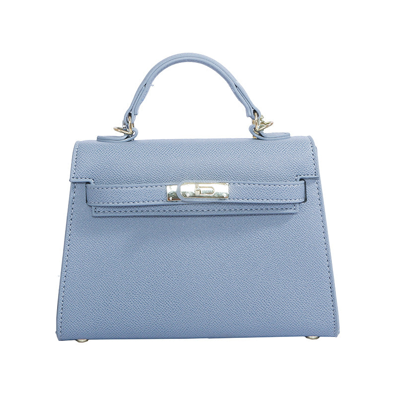 A woman carrying a small square bag with a lock