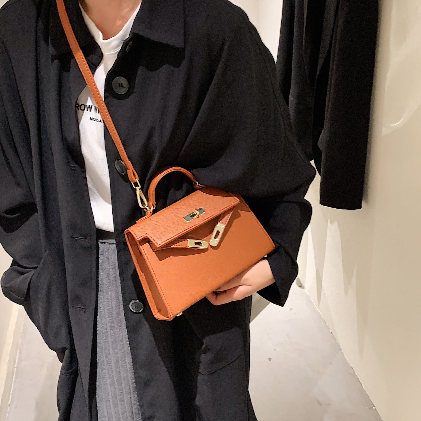 A woman carrying a small square bag with a lock