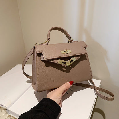 A woman carrying a small square bag with a lock