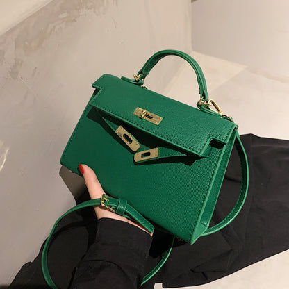 A woman carrying a small square bag with a lock